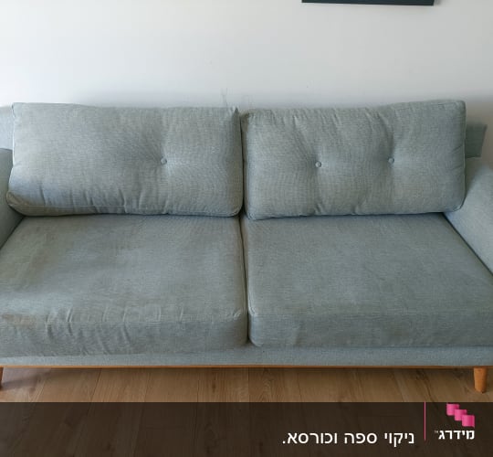ספה אפורה עם כתמים על רצפת עץ